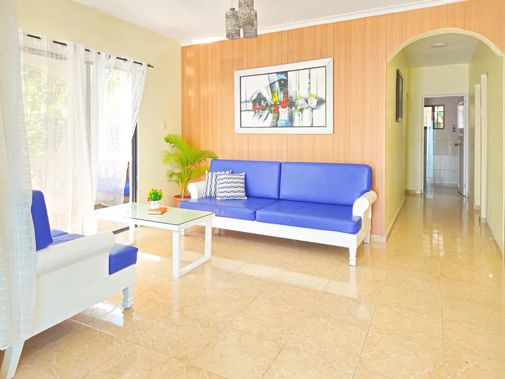 The living room with blue sofas and an archway through to the hall