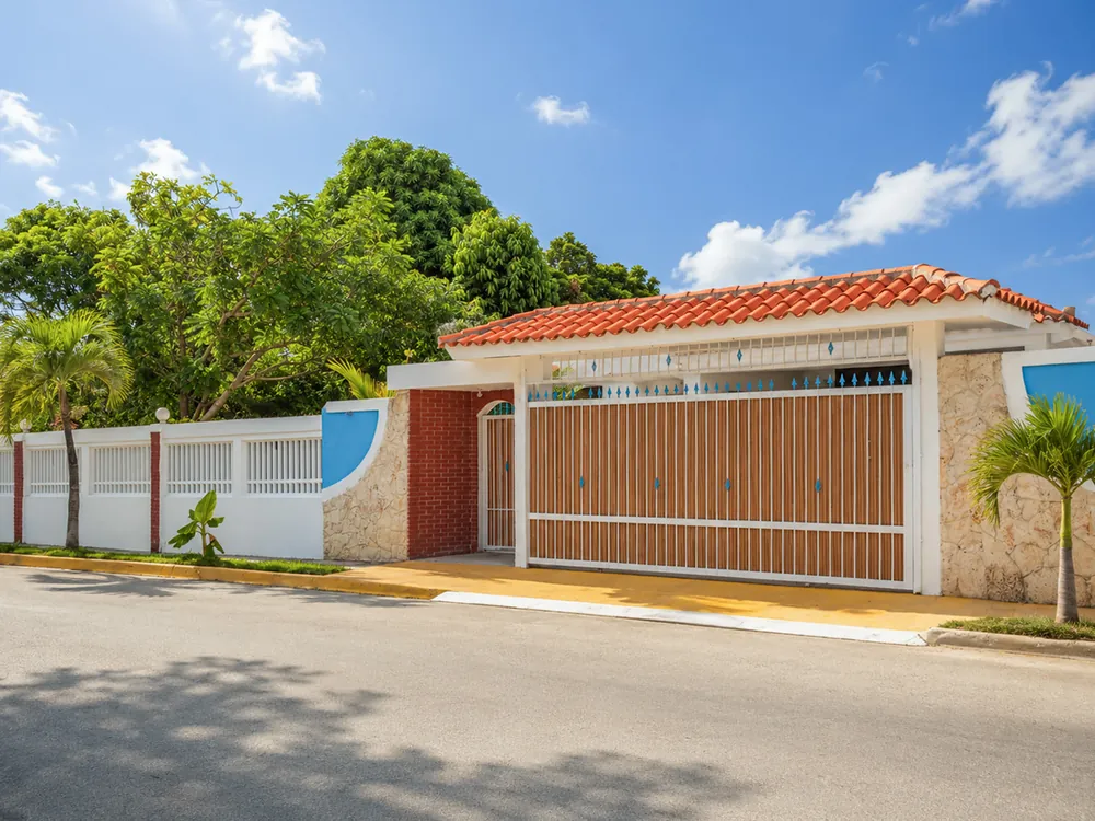 The villa from the street: white perimeter wall, red-tiled roof and its own gate