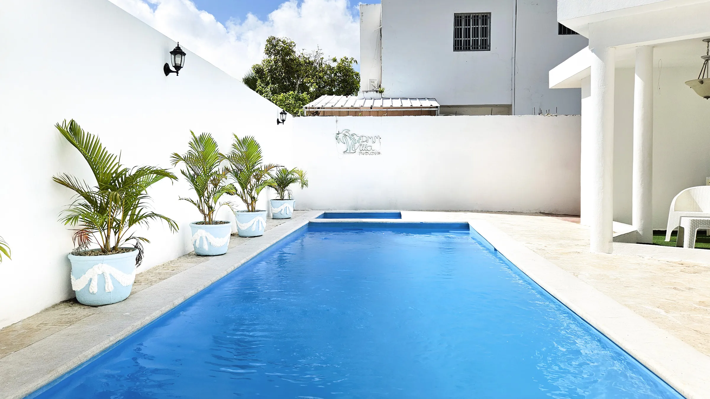 The private pool, lined with potted palms, seen along its length