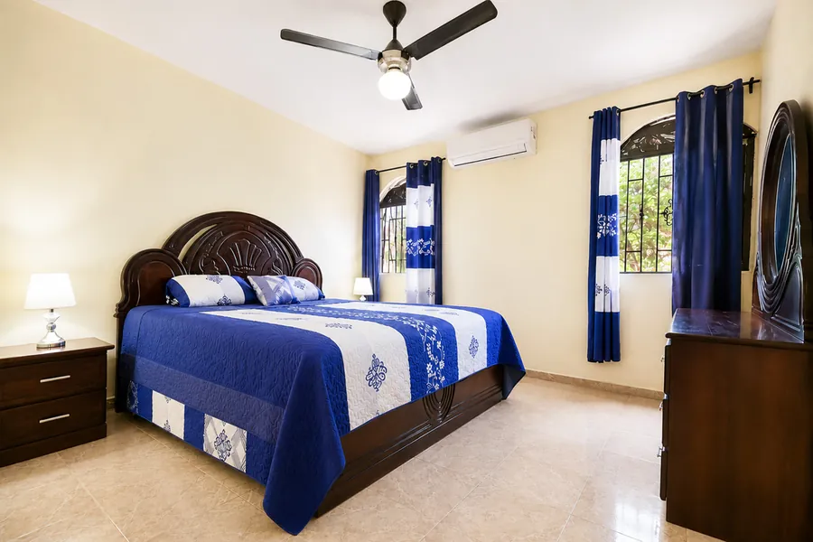 The main bedroom with a cobalt bedspread, ceiling fan and air conditioning