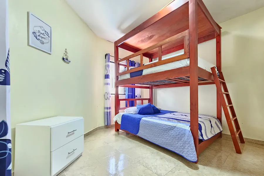 A bunk bed with a double below and a single above, beside a chest of drawers